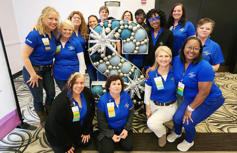 group of lades in blue shirts around the sterling S