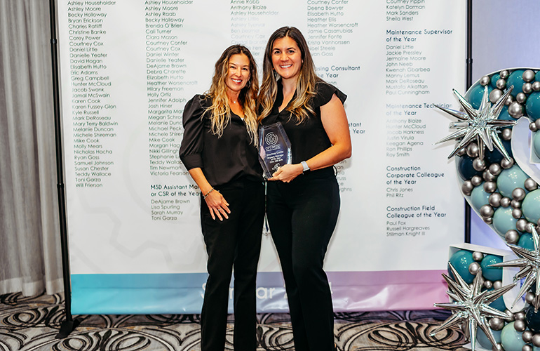 2 ladies standing together holding awards