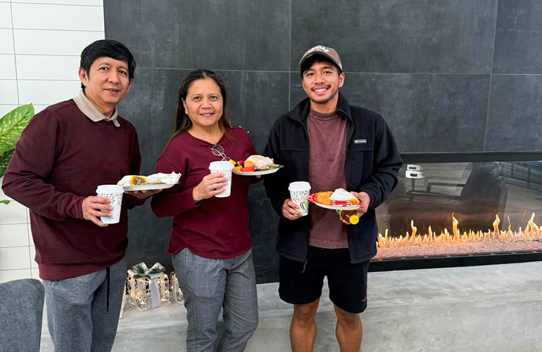 3 people standing together holding paper plates with food